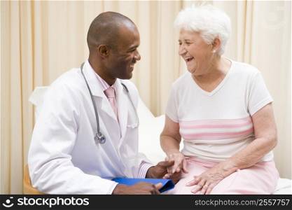 Doctor giving checkup to woman in exam room smiling