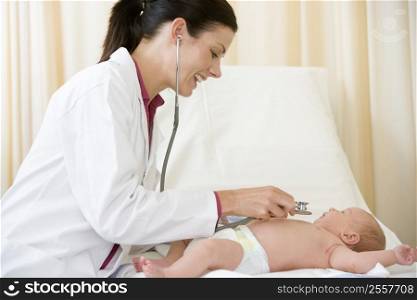 Doctor giving checkup with stethoscope to baby in exam room smiling