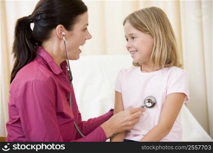 Doctor giving checkup with stethoscope to young girl in exam room smiling