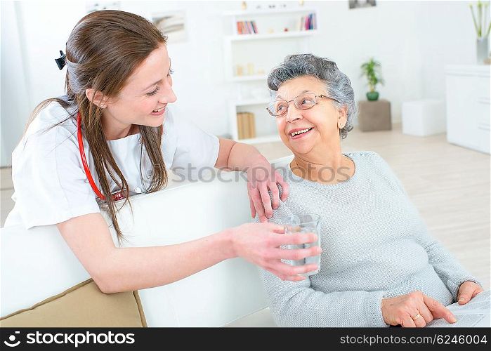 Doctor giving old lady a glass of water
