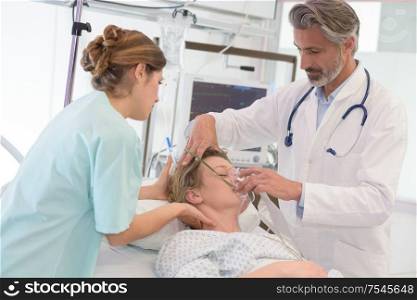 doctor giving oxygen mask to female patient at hospital