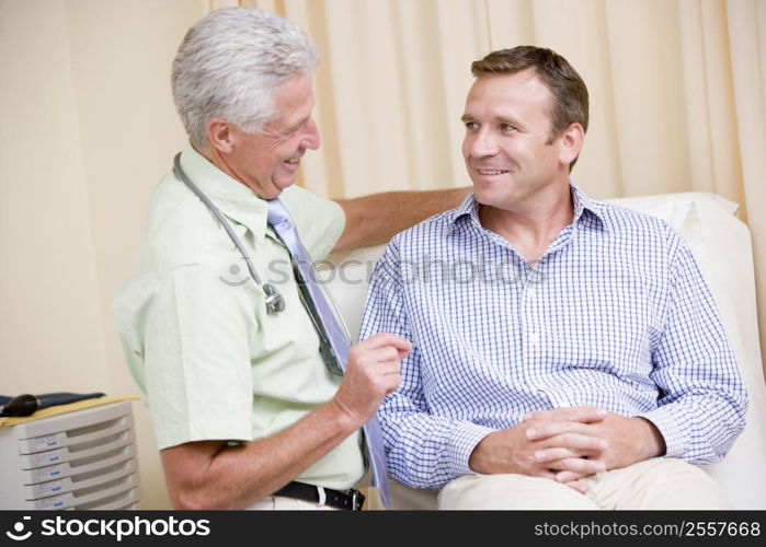 Doctor giving smiling man checkup in exam room