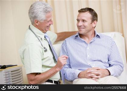Doctor giving smiling man checkup in exam room
