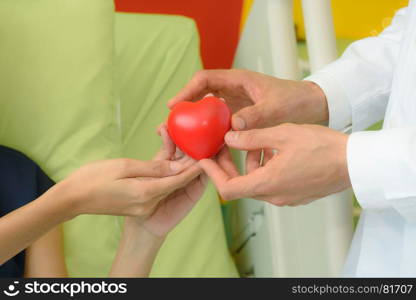doctor hand giving red heart to patient woman, healthcare concept