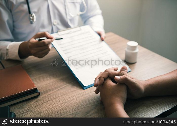 Doctor hand holding pen pointing patient history list on note pad and talking to the patient about medication and treatment.