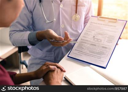 Doctor hand holding pen pointing patient history list on note pad and talking to the patient about medication and treatment.