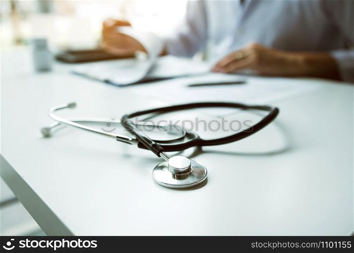 Doctor hand holding pen writing patient history list on note pad and talking to the patient about medication and treatment.
