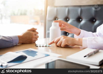 doctor hand holding tablet of drug and explain to patient in hospital room.