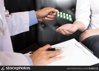 doctor hand holding tablet of drug and explain to patient in hospital room.