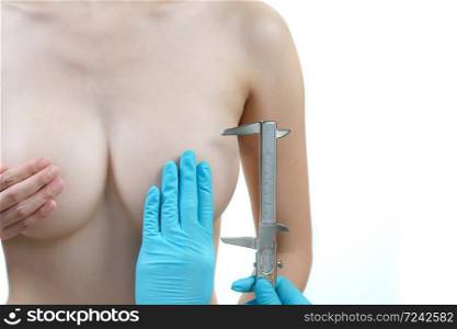 Doctor hand measurement woman breast with caliper, breast implant surgery concept.