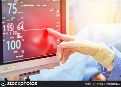 doctor hand touch on electrocardiogram showing patient heart rate in emergency room at hospital with blur background