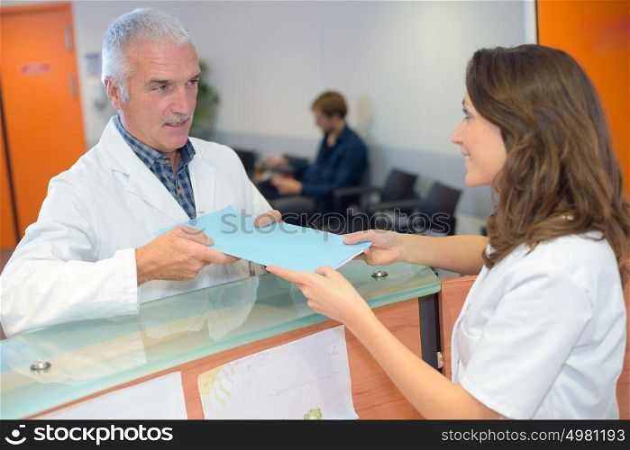 Doctor handing file to receptionist