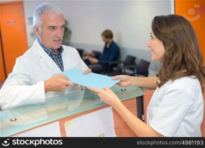 Doctor handing file to receptionist