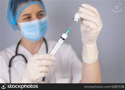 Doctor hands filling the syringe with vaccine. Medical treatment concept. Focus is on syringe.