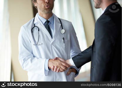 doctor handshake with a patient at doctors bright modern office in hospital