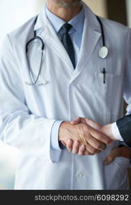 doctor handshake with a patient at doctors bright modern office in hospital