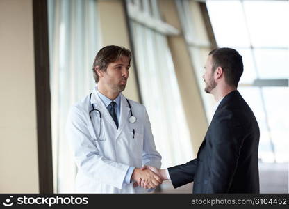 doctor handshake with a patient at doctors bright modern office in hospital