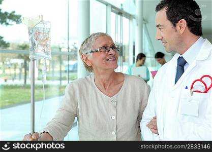 Doctor helping elderly patient in hall