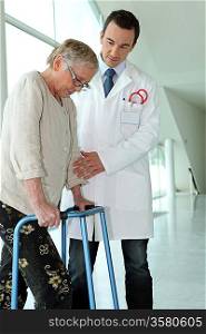 Doctor helping elderly patient with walking frame
