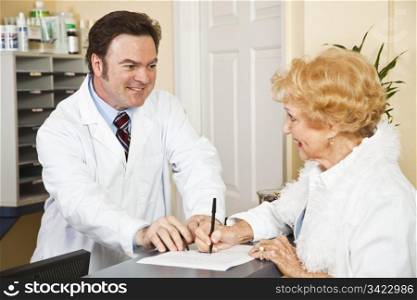 Doctor helps senior woman fill out paperwork in his office.