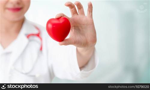 Doctor holding a red heart at hospital office. Medical health care and doctor staff service concept.
