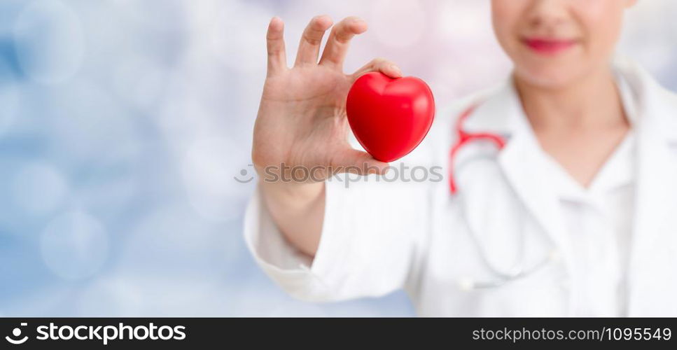 Doctor holding a red heart at hospital office. Medical health care and doctor staff service concept.