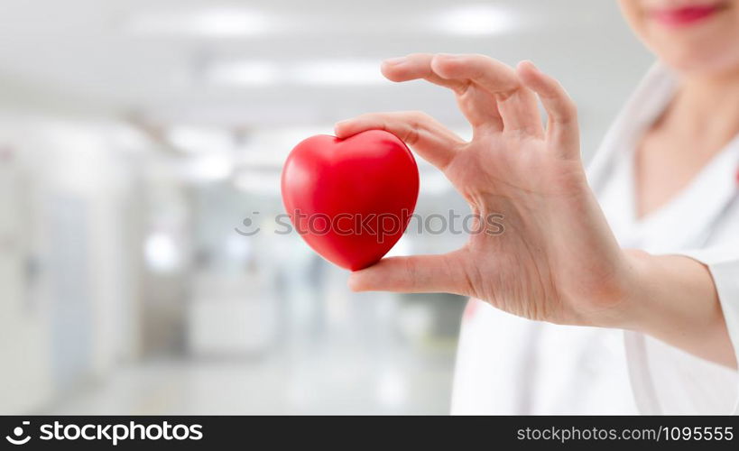 Doctor holding a red heart at hospital office. Medical health care and doctor staff service concept.