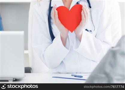 Doctor holding a red heart at hospital office, medical health care and doctor staff service concept. Doctor holding a red heart