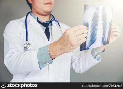 Doctor holding and checking chest x-ray film or roentgen image in ward hospital