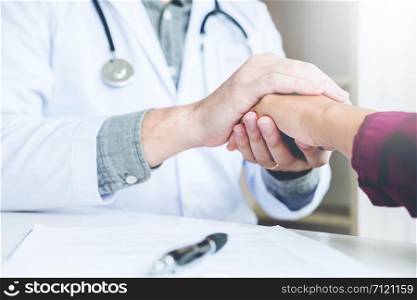 Doctor holding hands for comforting and care patient