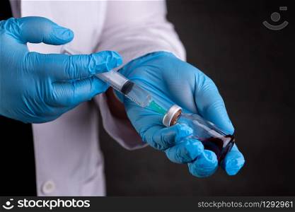 Doctor holding injection syringe and medicine in vial. Doctor holding syringe