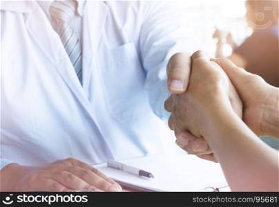 Doctor holding patient's hand, and reassuring his male patient helping hand concept.