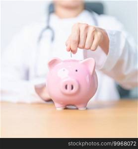 Doctor holding piggy bank and putting coin. and Healthcare cost, Money Saving, Health Insurance, Medical, Donation and Financial concepts