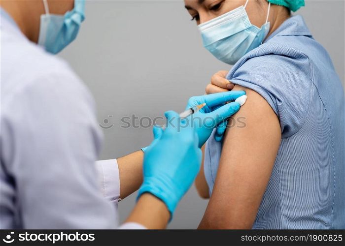 doctor holding syringe and using cotton before make injection to nurse or Medical professionals in a mask. Covid-19 or coronavirus vaccine