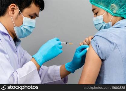 doctor holding syringe and using cotton before make injection to nurse or Medical professionals in a mask. Covid-19 or coronavirus vaccine