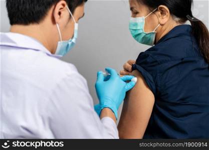 doctor holding syringe and using cotton before make injection to woman in a medical mask. Covid-19 or coronavirus vaccine
