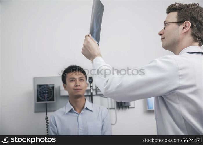 Doctor holding up and looking at x-ray of patient