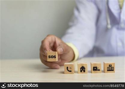 Doctor holding wood cube block sos icon health care business concept on desk.