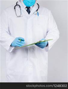 doctor in a white coat and medical blue gloves records a patient&rsquo;s medical history, close up
