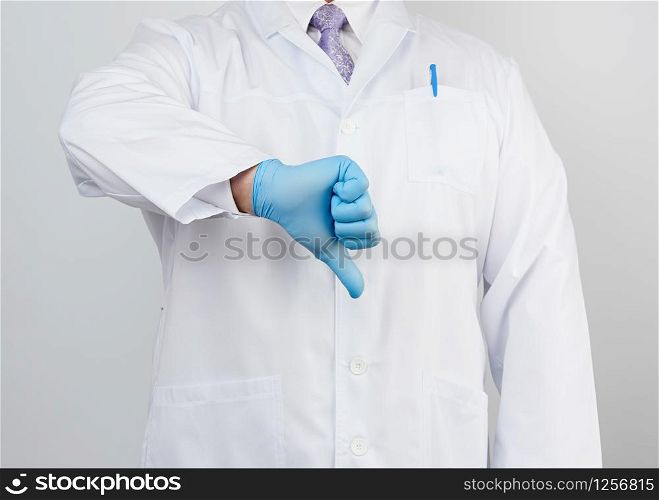 doctor in a white coat with buttons shows a gesture of dislike with his hand, wearing blue medical glove, emotion of negativity