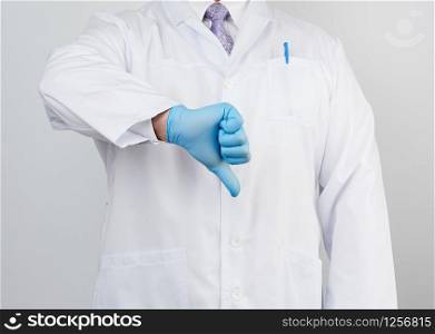 doctor in a white coat with buttons shows a gesture of dislike with his hand, wearing blue medical glove, emotion of negativity