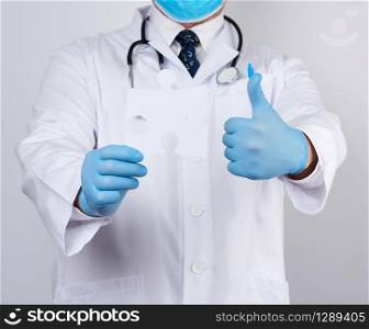 doctor in a white medical coat and blue rubber gloves holds a white paper puzzle, close up