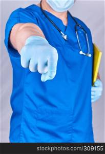 doctor in blue uniform and latex gloves showing hand gesture, gray background