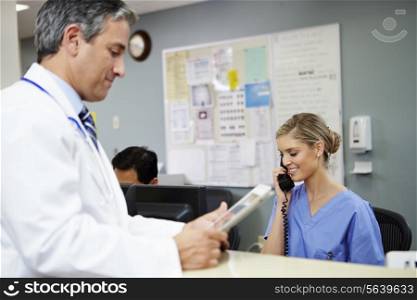Doctor In Discussion With Nurse At Nurses Station
