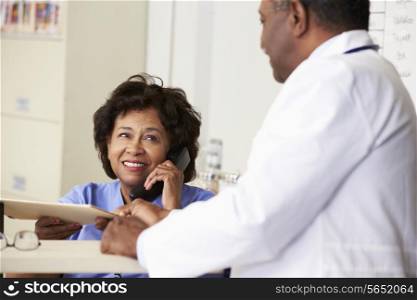 Doctor In Discussion With Nurse At Nurses Station