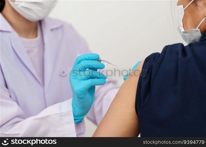 doctor in gloves holding syringe and making injection to patient in medical mask. Covid-19 or coronavirus vaccine