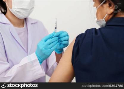doctor in gloves holding syringe and making injection to patient in medical mask. Covid-19 or coronavirus vaccine