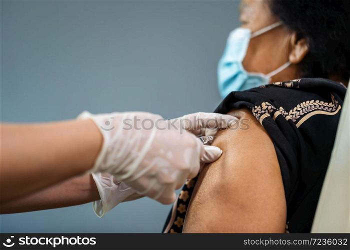 doctor in gloves holding syringe and making injection to senior patient in medical mask. Covid-19 or coronavirus vaccine