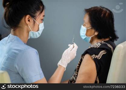 doctor in gloves holding syringe and making injection to senior patient in medical mask. Covid-19 or coronavirus vaccine