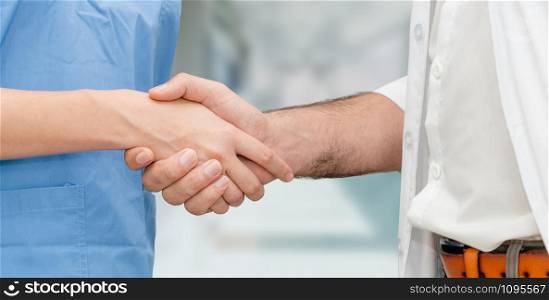 Doctor in hospital handshake with another doctor. Healthcare people teamwork and medical service concept.